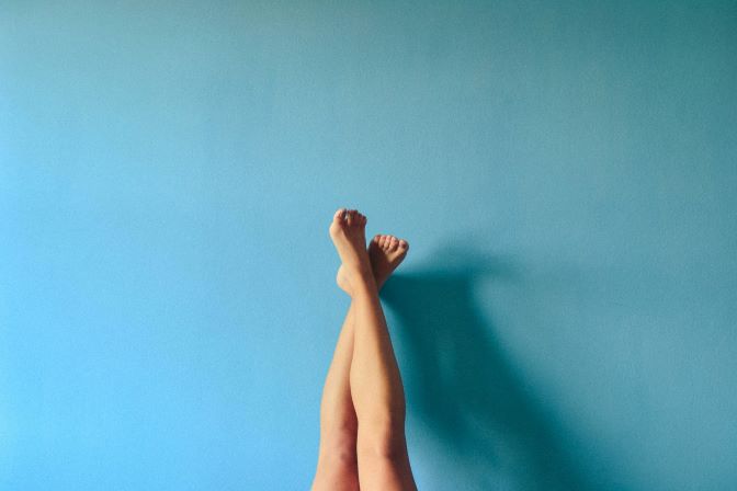 A photo of feet against a blue wall.